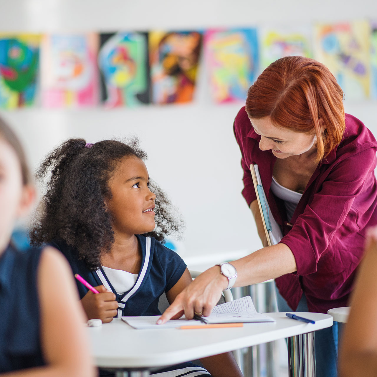 Une enseignante ou un enseignant est en train d'aider un élève dans son travail.
